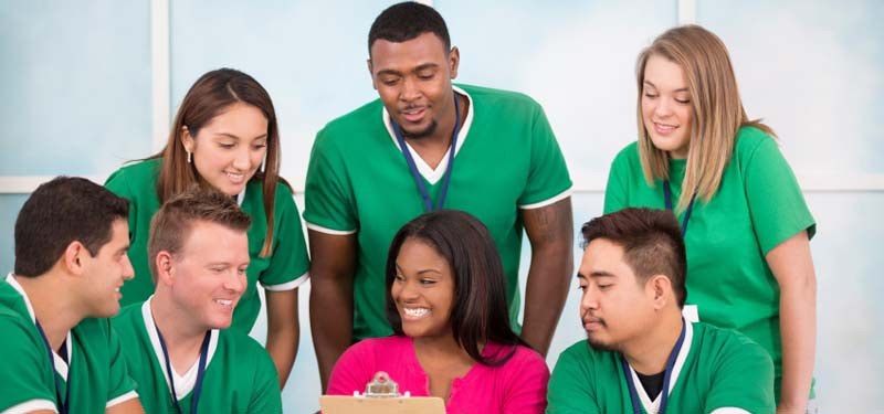 Nurses Working Together at a Desk Looking at Clipboard